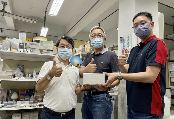 From left, National Taipei University of Technology associate professor Shao Wen-cheng, professor Cheng Ta-wei and assistant professor Lee Wei-hao hold a brick made from oyster shells and furnace slag at the university on Friday.